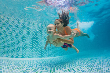 Happy family - mother, father with baby boy swimming, diving underwater with fun in blue pool....