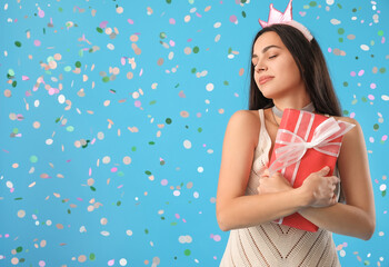 Obraz na płótnie Canvas Happy young woman with Birthday gift on blue background