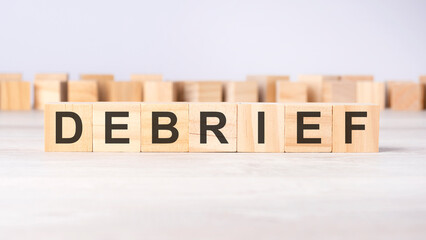 word DEBRIEF inscribed on wooden cubes lying on a light table. economy and investments concept.