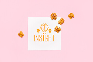 Paper with word INSIGHT and walnuts on pink background