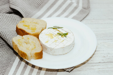 White baguette cut into pieces with olive oil and Camembert cheese on the table.