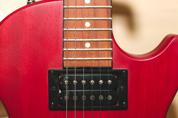Red electric guitar with strings close up.