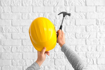 Worker with hammer and hardhat on white brick background