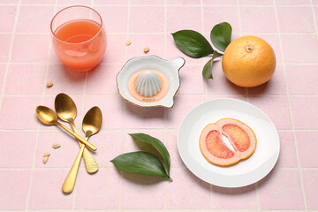 Composition with ripe grapefruit, glass of juice and plant leaves on color tile background