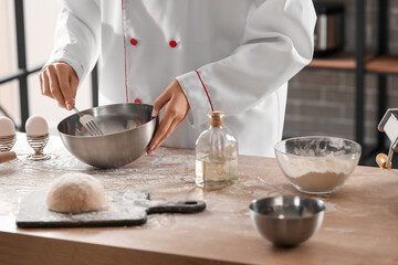 Female chef making dough for pasta at table in kitchen, closeup