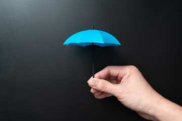 Hand holding mini blue umbrella