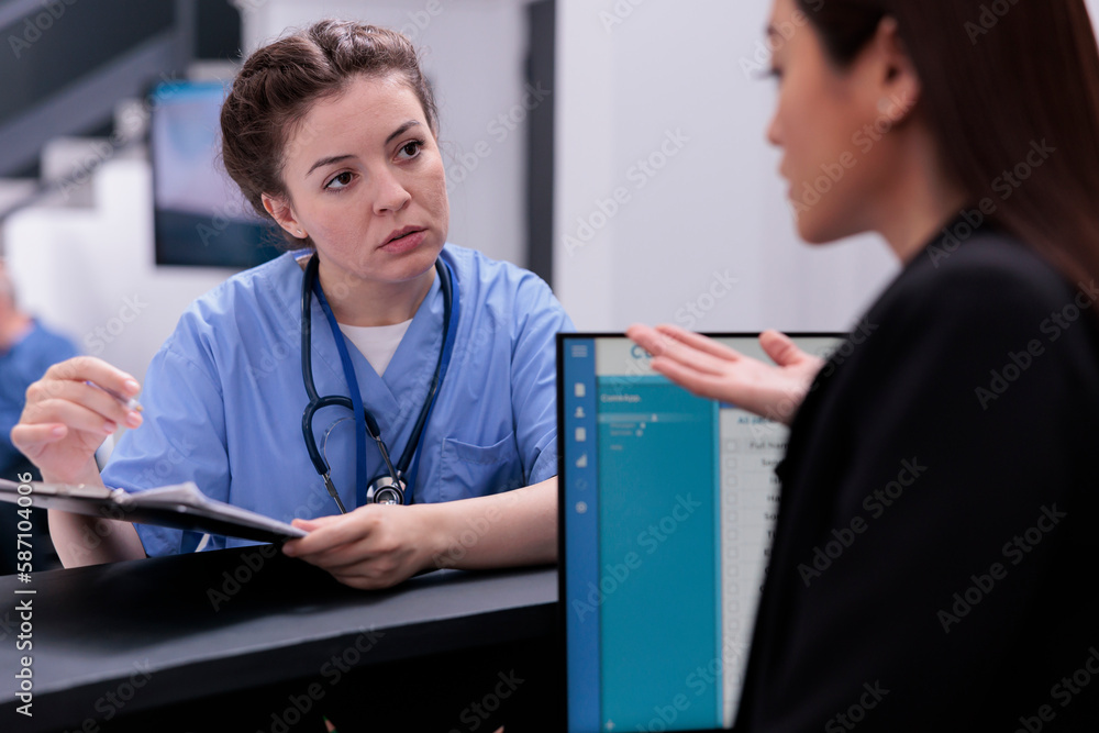 Poster medical assistant showing patient expertise to receptionist while asking her to programming another 