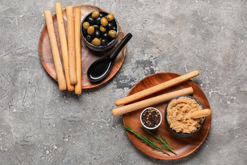 Plates with tasty Italian Grissini and hummus on grunge background
