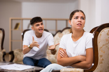 Portrait of frustrated woman in living room, while disgruntled husband scolds her
