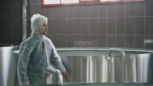 A brewery employee controls the process of brewing beer in a huge steel tanks in brewery factory