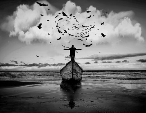 Grayscale photo of man standing on a boat under flying birds