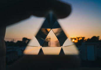 Hand holding crystal pyramid during sunset