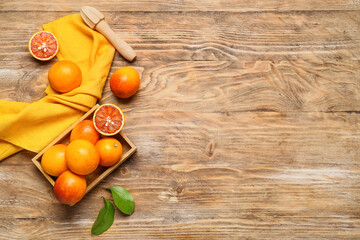 Box with tasty blood oranges and yellow napkin on wooden background