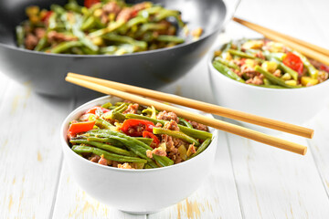 Szechuan style stir-fry pork cooked in sauce and vegetables close up in the plate on the wooden table.