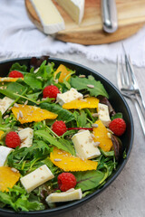 vegetarian fresh green salad with brie cheese, oranges and raspberries