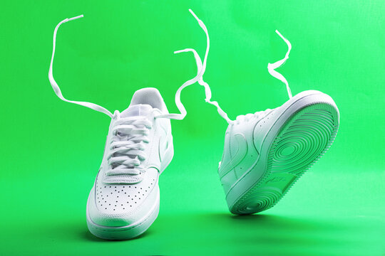 Flying white sneaker Nike on green background. Fashionable stylish leather sports casual shoes.