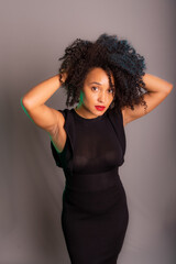 Portrait of beautiful young brunette woman messing with her hair. Dressed in black.