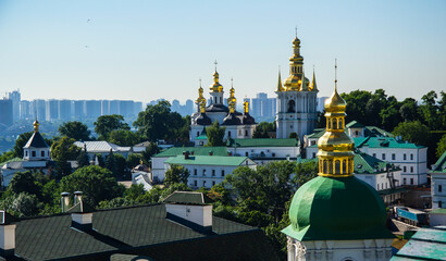 Fototapeta na wymiar Kiev-Pechersk Lavra against the backdrop of skyscrapers on the left bank of the Dnieper in Kyiv. Panorama of the Lower Lavra with the Bell Tower on the Far Caves. UNESCO World Heritage Site in Ukraine