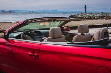 Red convertible car with the top down stopped on the beach. Closeup view of luxury convertible car...