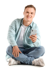 Young man with smartphone sitting on white background