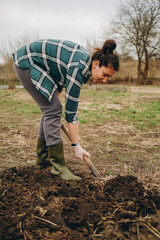 A woman is digging the earth in a field. Agricultural work in the spring in the field. Preparing the land for planting sheep in the spring.