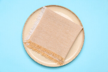 Plate with folded napkin on color background