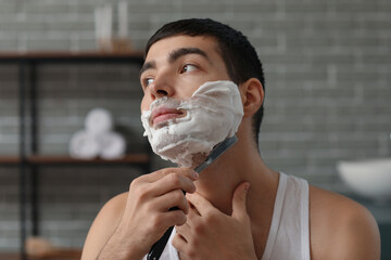 Young man shaving in bathroom