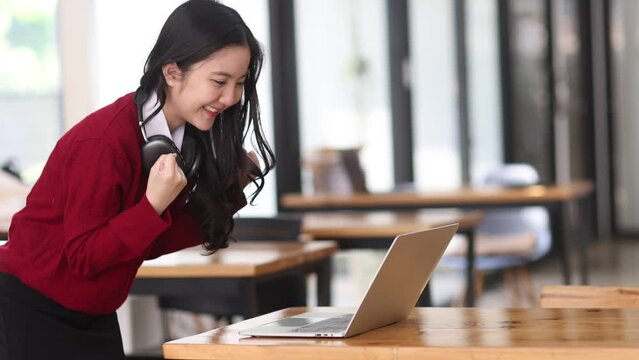 Asian woman worker feeling excited and euphoric winning, Young woman excited sitting at desk office, Overjoyed woman, Attractive woman triumph sit at desk with laptop computer win online.