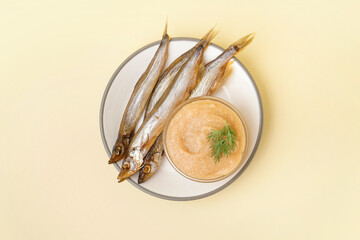 Plate with bowl of caviar and smoked capelin fishes on beige background