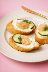 Delicious canapes with caviar of capelin on pink background