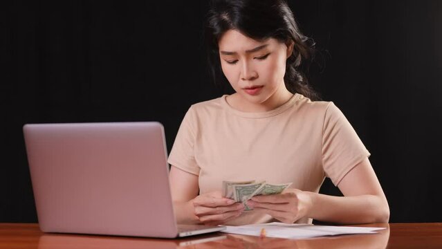 Asina woman counting her money while trying to pay her bills.