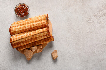 Board of wafer rolls with boiled condensed milk on grey grunge background