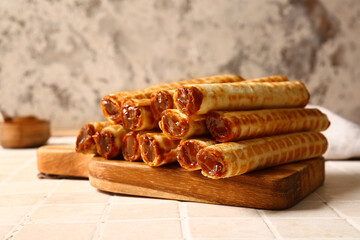 Board of wafer rolls with boiled condensed milk on tile table