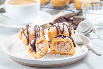 Profiteroles with whipped cream and chocolate filling, with melted chocolate, cutted, horizontal