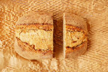 Fototapeta na wymiar Halves of fresh bread loaf on parchment paper