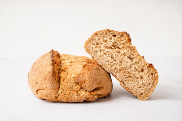 Sliced loaf of fresh bread on white table