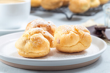 Profiteroles with whipped cream and chocolate filling, covered with icing sugar, horizontal