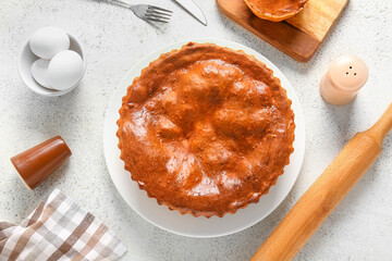 Composition with delicious meat pie, eggs and rolling pin on white grunge table