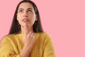 Thoughtful young woman on pink background, closeup