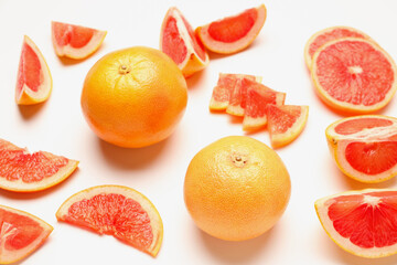Composition with cut and whole ripe grapefruits on white background