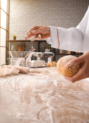 Female chef preparing dough for pasta at table in kitchen, closeup