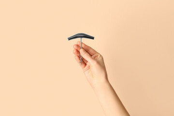 Female hand holding corkscrew on beige background