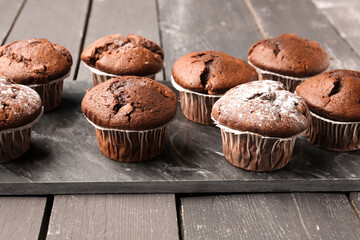 Board with tasty chocolate cupcakes on dark wooden background