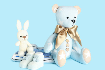Obraz na płótnie Canvas Toy bear and bunny with baby clothes on blue background