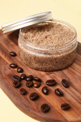 Wooden board with jar of body scrub and coffee beans on color background, closeup