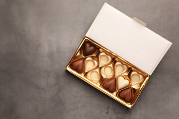 Partially empty box of chocolate candies on grey background, top view. Space for text