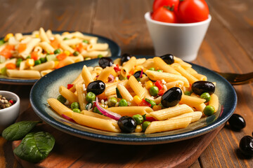 Plates with tasty pasta salad on wooden background