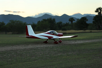 Ultralight airplane on green grass near beautiful mountains