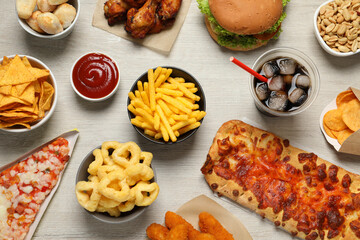 French fries, onion rings and other fast food on white wooden table, flat lay