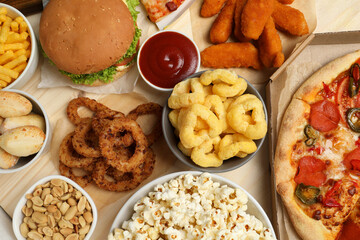 Pizza, chicken nuggets and other fast food on wooden table, flat lay